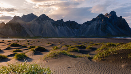 Majestic Vestrahorn Mountain Range at sunset with sandy dunes and grassy patches in Iceland