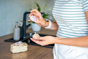 Hands of young woman holding Chinese single clove garlic and regular multi clove garlic, choosing ingredient for cooking. Culinary selection, natural food, and kitchen preparation.
