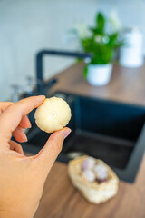 Female hand holding peeled Chinese single clove garlic. Fresh ingredient, natural flavor, and kitchen preparation.