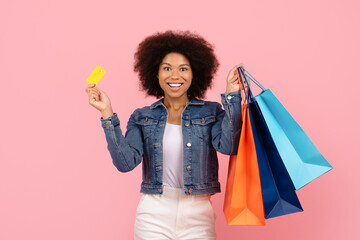 Smiling African American woman holding credit card and shopping bags. Concept of online payment,...