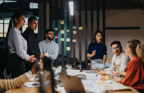 Diverse professionals discussing ideas and projects during a workplace meeting. The atmosphere is dynamic and collaborative, with various people contributing to the conversation in a modern office