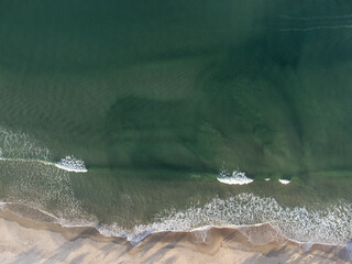 top view of turquoise blue beach with waves forming