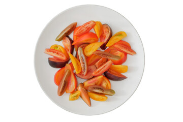 Sliced tomato in white plate. Tomatoes in a clay plate isolate on white background. Orange and red ripe vegetables. Top view.