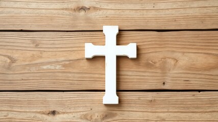 Minimalist white cross rests on a rustic wooden surface evoking themes of faith, belief and spirituality