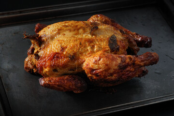 Roasted whole chicken on a black metal tray rustic photography