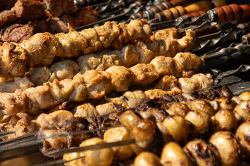 A variety of meats and vegetables are being cooked on a grill