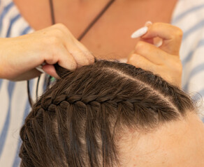 Fototapeta premium A woman is braiding a woman's hair
