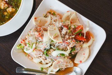 Close-up of Thai food, glass noodle salad, a spicy Thai salad that uses glass noodles as the main ingredient. The food is arranged on a white square plate, looking clean and appetizing.
