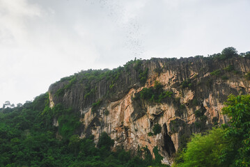 A view of large limestone mountains covered with dense green forest. Limestone mountains are characterized by steep cliffs, natural cracks and fissures that reveal different layers of rock.
