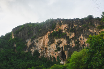A view of large limestone mountains covered with dense green forest. Limestone mountains are characterized by steep cliffs, natural cracks and fissures that reveal different layers of rock.