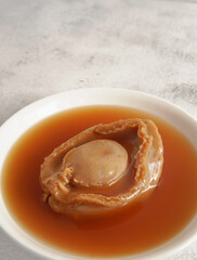 Big abalone with brown sauce on a white plate