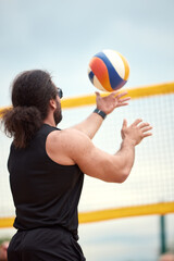 Man playing volleyball at a sports court under a clear sky