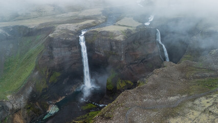 Majestic Haifoss waterfalls cascading through rugged Icelandic geology under a misty sky