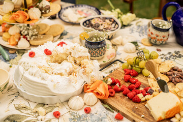 Smashed whipped cream cake and cheese board with fruit on picnic table