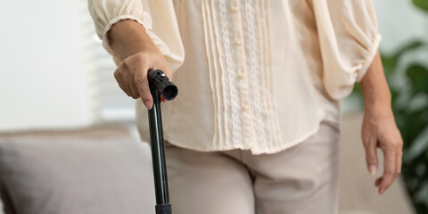 Elderly woman using cane for support in home environment