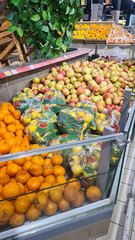 A vibrant display of fresh fruits and vegetables in a market. Includes oranges, apples, and assorted greens. Ideal for healthy eating concepts.
