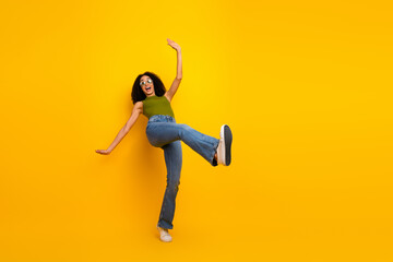 Cheerful young woman in casual outfit posing with energy against a vibrant yellow background