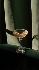 Elegant cocktail in vintage glass against dark green velvet background