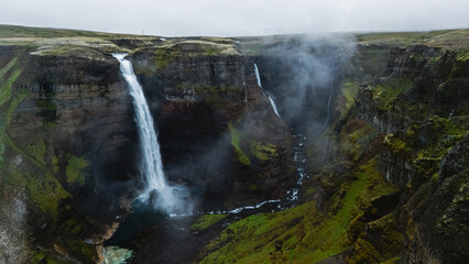 Majestic Haifoss waterfalls cascading into a lush green canyon in Iceland during overcast weather