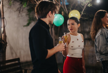 Friends engaging in conversations and enjoying drinks at an outdoor evening gathering event.