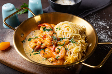 Pasta with shrimps in creamy sauce in a pan close up