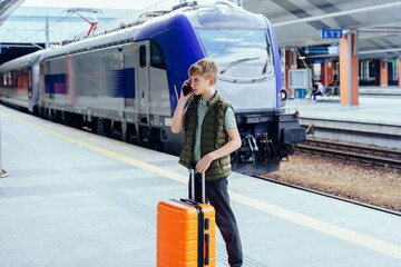 Teen boy talking on phone after train arrives
