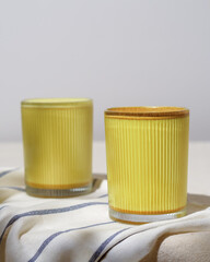 Two glasses of golden turmeric latte glow in bright daylight on striped fabric, inviting to enjoy a fresh healthy start of the day.