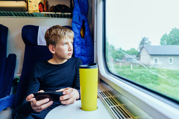 Teen boy watching landscape through train window