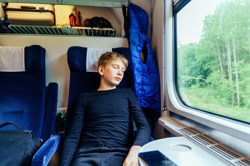 Teen boy sleeping during train ride near window
