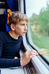 Teen boy focused on forest view from train window