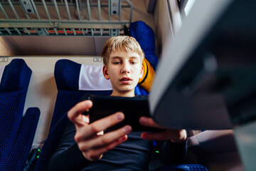 Teen boy focused on smartphone while riding train