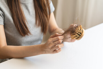 Close-up young woman brushing her hair and have many hair loss on the comb
