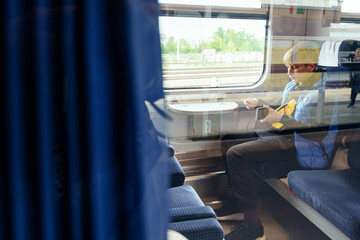 Reflection of teen using phone at train window