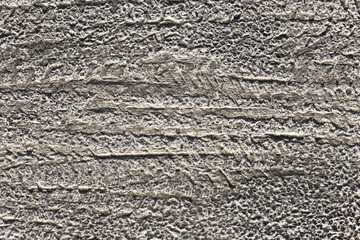 Grunge asphalt texture background. Closeup view of road surface with tire tracks and rough structure. Worn and dirty grey pavement. Urban infrastructure detail. Concrete street material concept.
