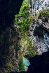 High-angle view of forest and river flowing through Taroko National Park, Taiwan. Clear blue water streams over rocks with moss in the crevices of the mountain. Idea for a nature background.