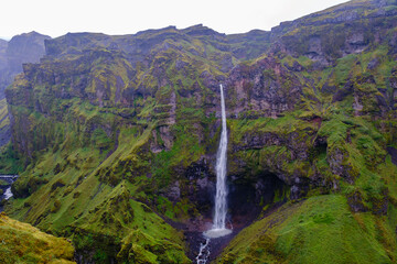 Majestic Mulagljufur Canyon waterfall amidst lush green landscapes of Icelandic wilderness