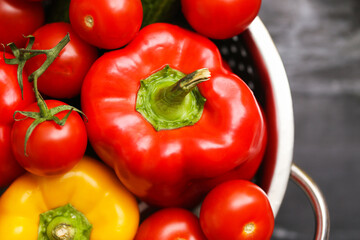 Fresh bell pepper and tomatoes. Closeup view of colorful vegetables in metal colander. Red and yellow paprika with cherry tomatoes. Healthy organic food. Natural ingredients for cooking salad.