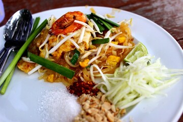 Traditional Pad Thai Noodles with Shrimp, Lime, and Toppings on a White Plate - Authentic Thai Street Food