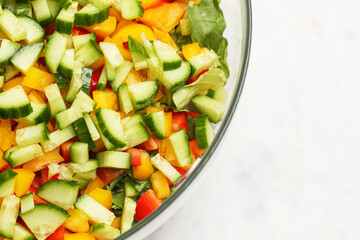 Fresh chopped vegetable salad. Bowl with cucumber, lettuce and sweet pepper mix. Colorful healthy meal. Bright diced ingredients in glass bowl isolated on white empty copy space.
