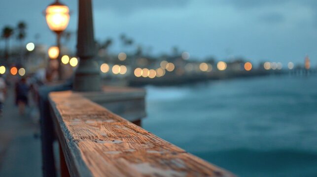 Wooden boardwalk railing overlooking a coastal city at twilight.