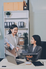 Entrepreneur Asian businessman and businesswoman discussing new business project in tablet in modern Meeting In Modern Office, Asian business casual concept.
