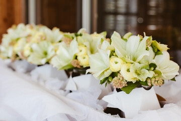 Elegant floral arrangements in pastel yellow pallette displayed on a table for a special occasion in a serene indoor setting