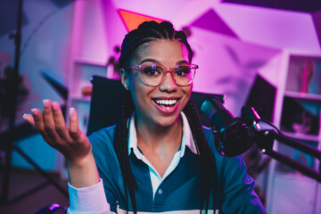 Young woman hosting live podcast with microphone in a brightly lit home studio creating engaging...