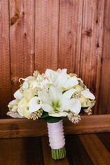Beautiful white floral bouquet arranged with elegant lilies for a wedding or special occasion in a rustic setting