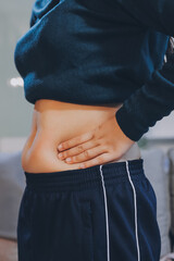 woman's hand holding excessive belly fat, overweight concept