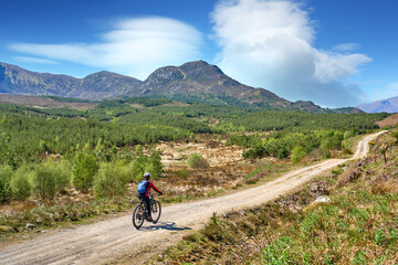 Fototapeta premium nice senior woman riding her electric mountain bike in the highlands of Glen Affric Nature reserve, Scotland, UK