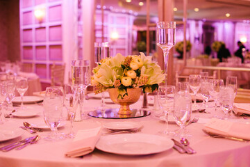 Elegant dining setup with floral centerpiece at a banquet hall during evening event