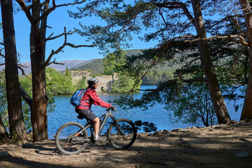 nice senior woman riding her electric mountain bike at Loch An Eilein in the Cairn Gorms National Park near Aviemore Scotland, UK
