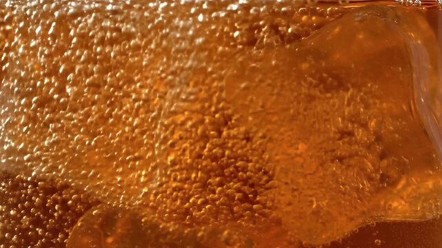 Captivating close up of sparkling golden amber liquid with energetic effervescent bubbles and submerged ice a refreshing cool beverage texture background