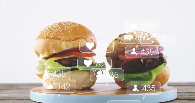 Stacking beef burgers layering lettuce tomato cheese onion on wood board, with social media icons - Powered by Adobe
